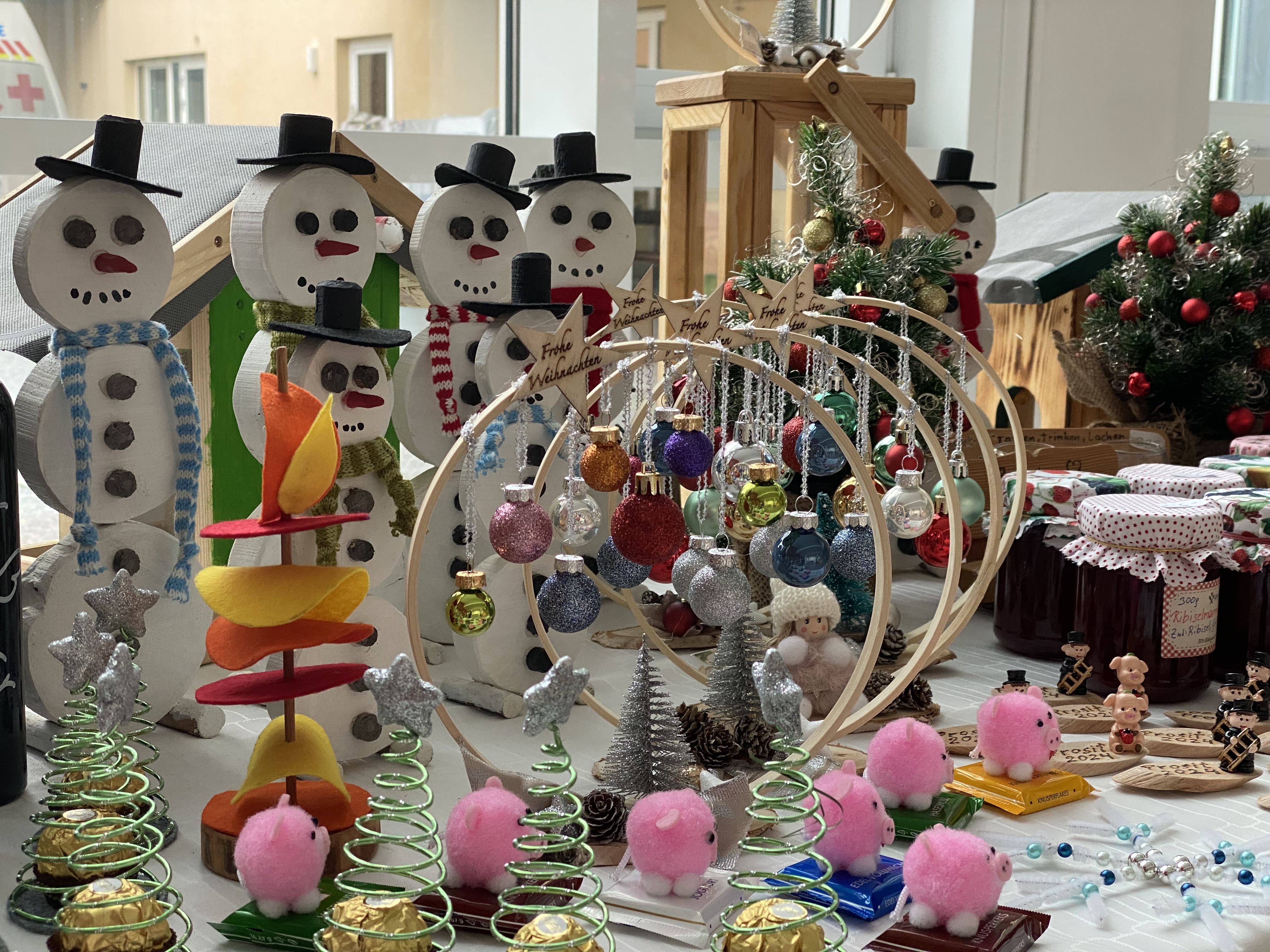 Adventmarkt-Stand mit handgemachter, weihnachtlicher Dekoration wie Schneemännern, Weihnachtskugeln und Weihnachtsbäumen