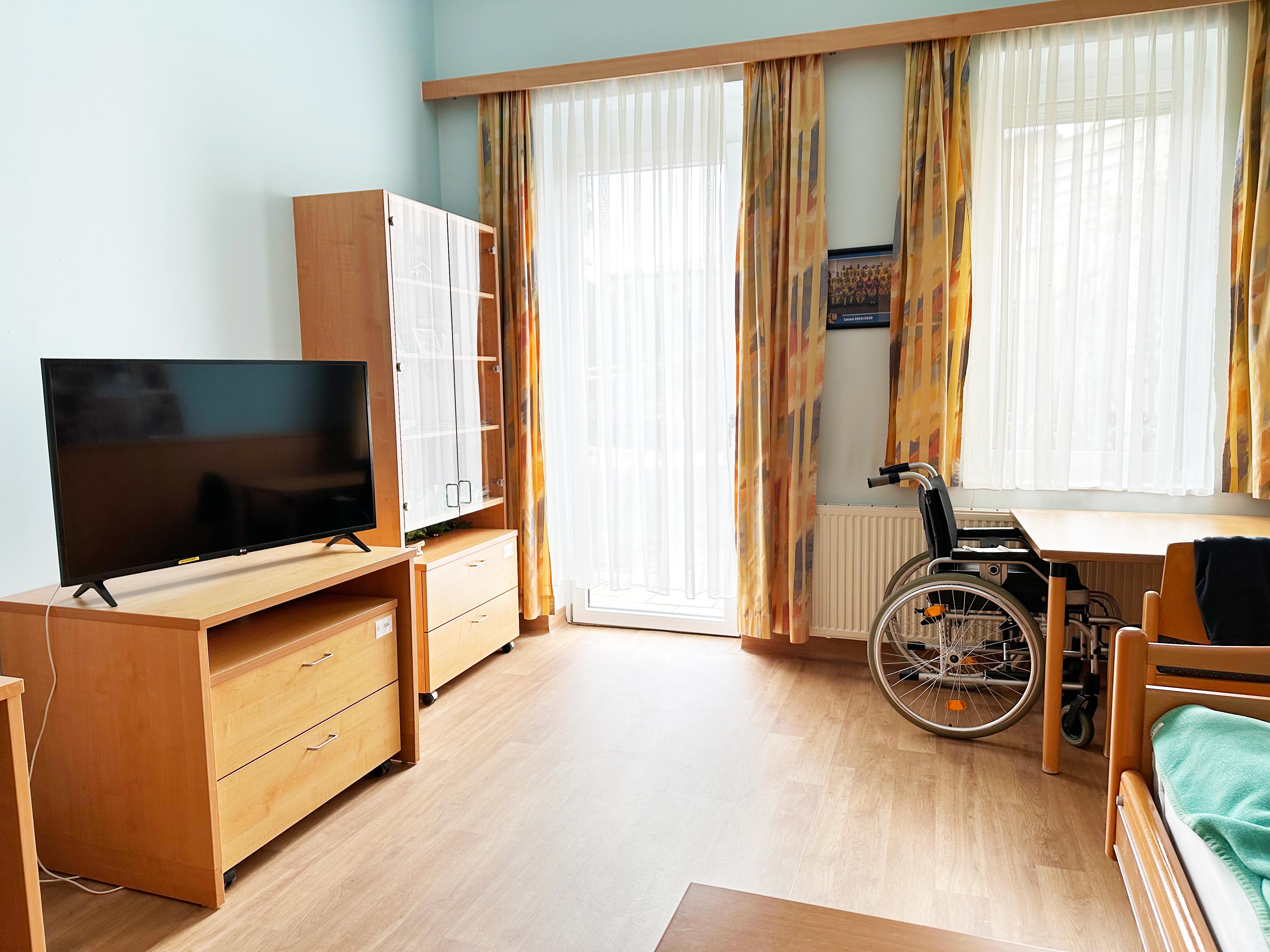 Helles Zimmer mit bunten Vorhängen, Sitzecke, TV und Schränken