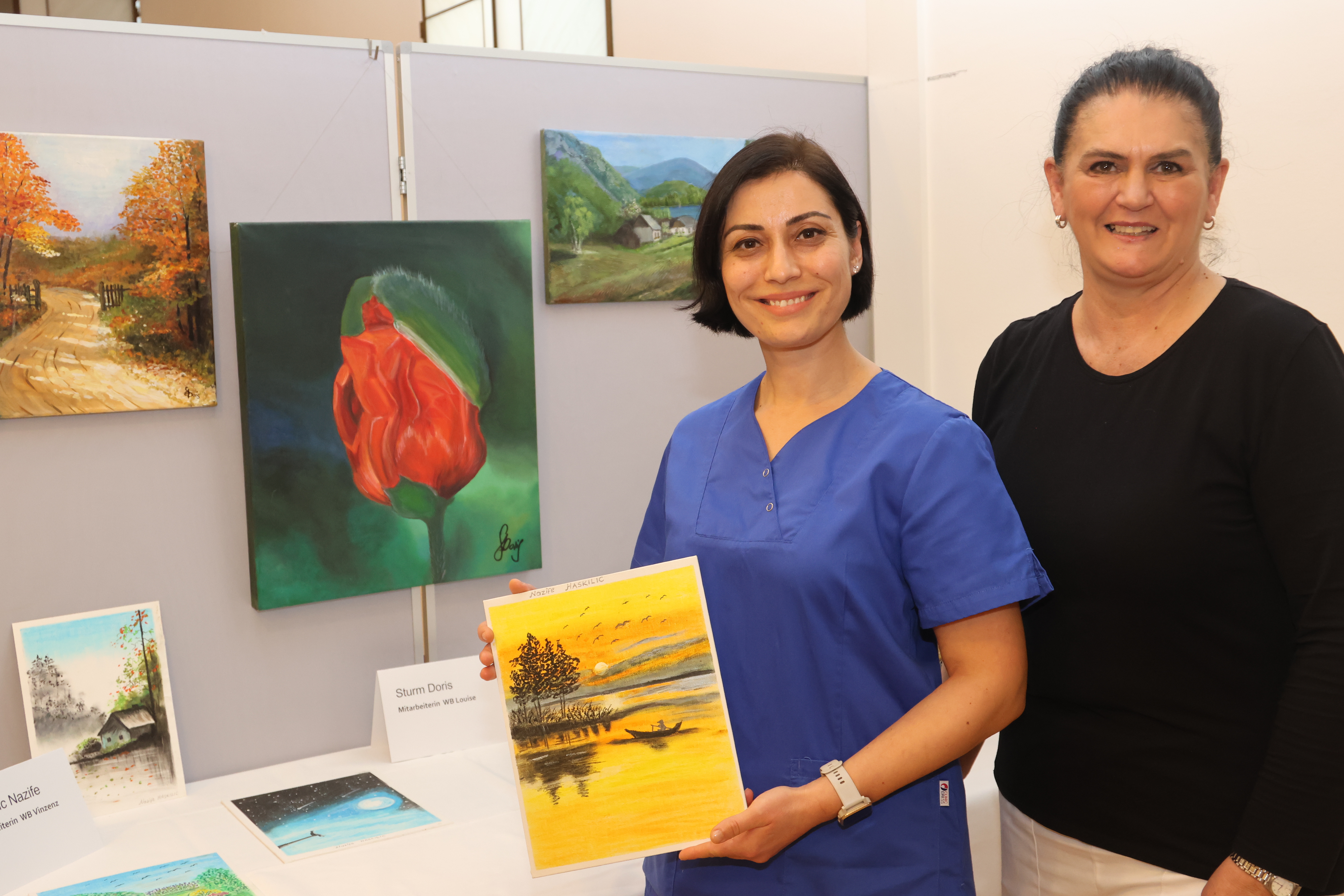 Zwei Pflegemitarbeiterinnen präsentieren ihre Kunstwerke