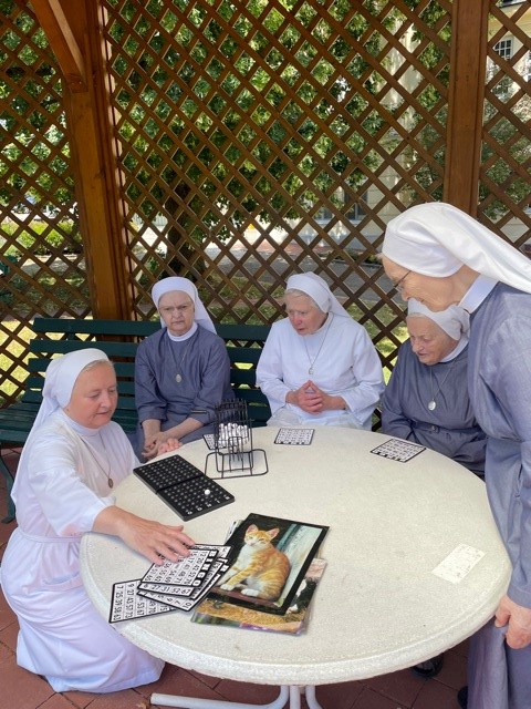 Fünf Ordensfrauen spielen zusammen Bingo im Garten