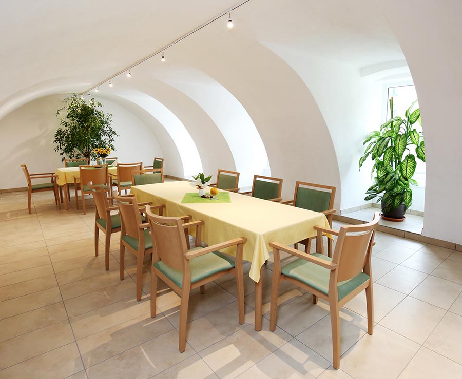 Gemütlicher Gemeinschaftsraum mit Tisch mit vielen Sitzmöglichkeiten und Pflanzen.