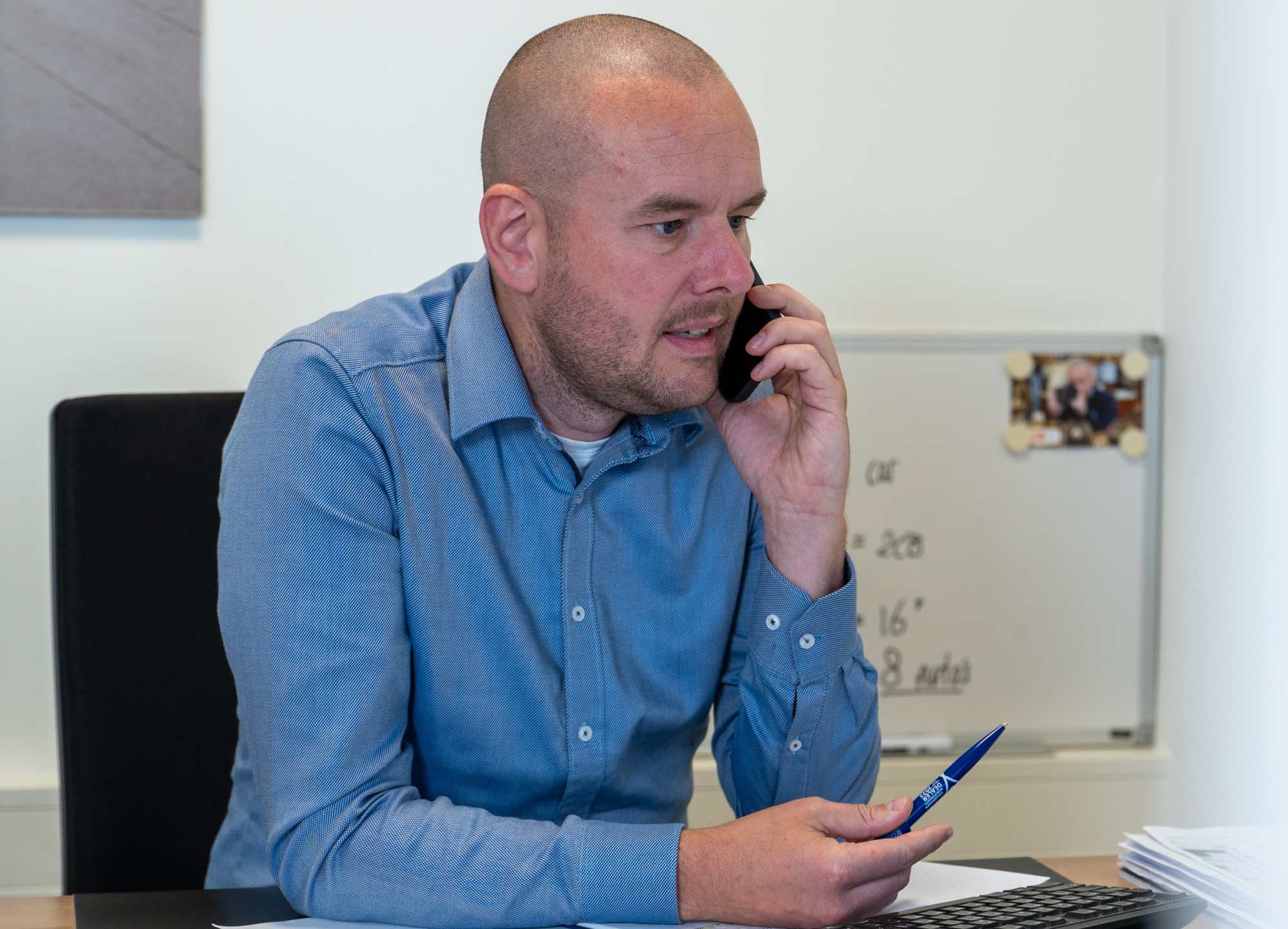 Man zittend aan bureau aan de telefoon.