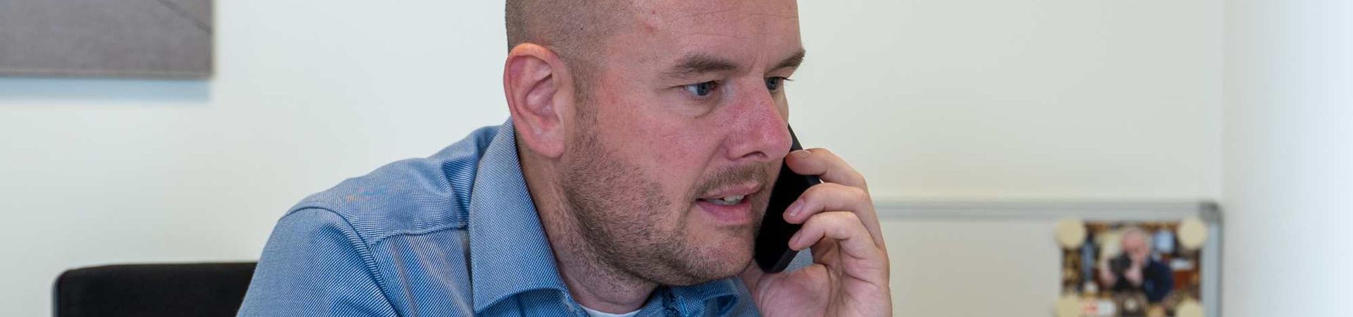 Man zittend aan bureau aan de telefoon.