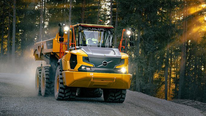 Yellow electric articulated hauler driving on a gravel forest road