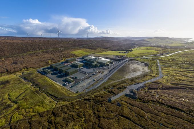 Aerial view of a Kergod surrounded by vast open landscape and wind turbines.