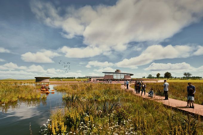 Visitors on a wooden boardwalk through marsh with wildflowers and reeds