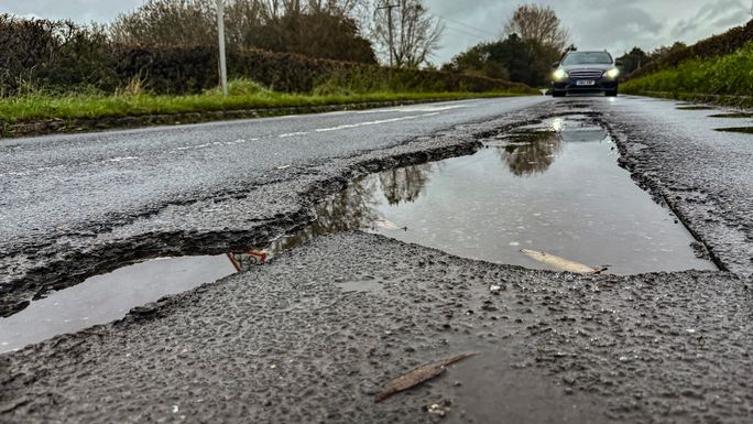 Large pothole filled with water on a rural road