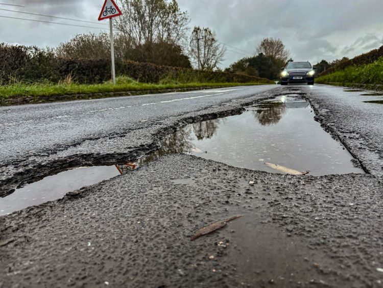 Large pothole filled with water on a rural road
