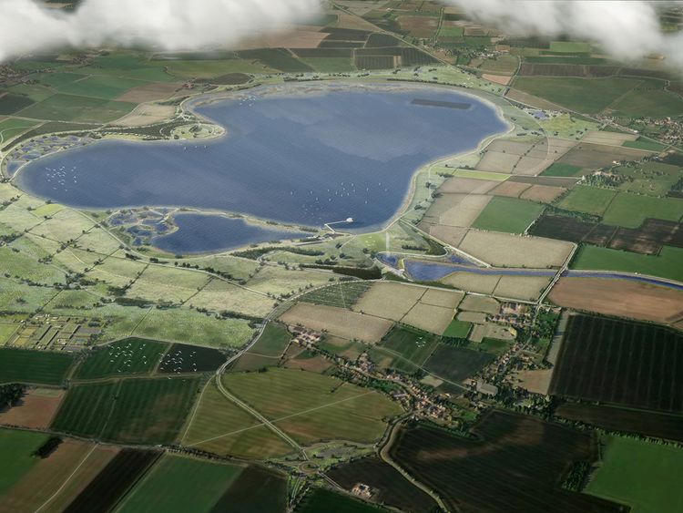 Aerial view of a large lake surrounded by patchwork fields. Paths and waterways crisscross the landscape.