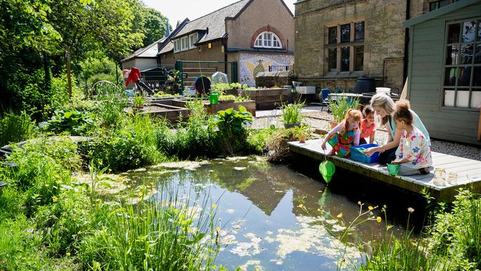 woman and children sit by a pond with a net
