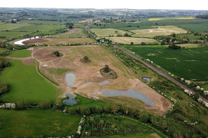 Aerial view of farmland with a large bare field containing several flooded areas