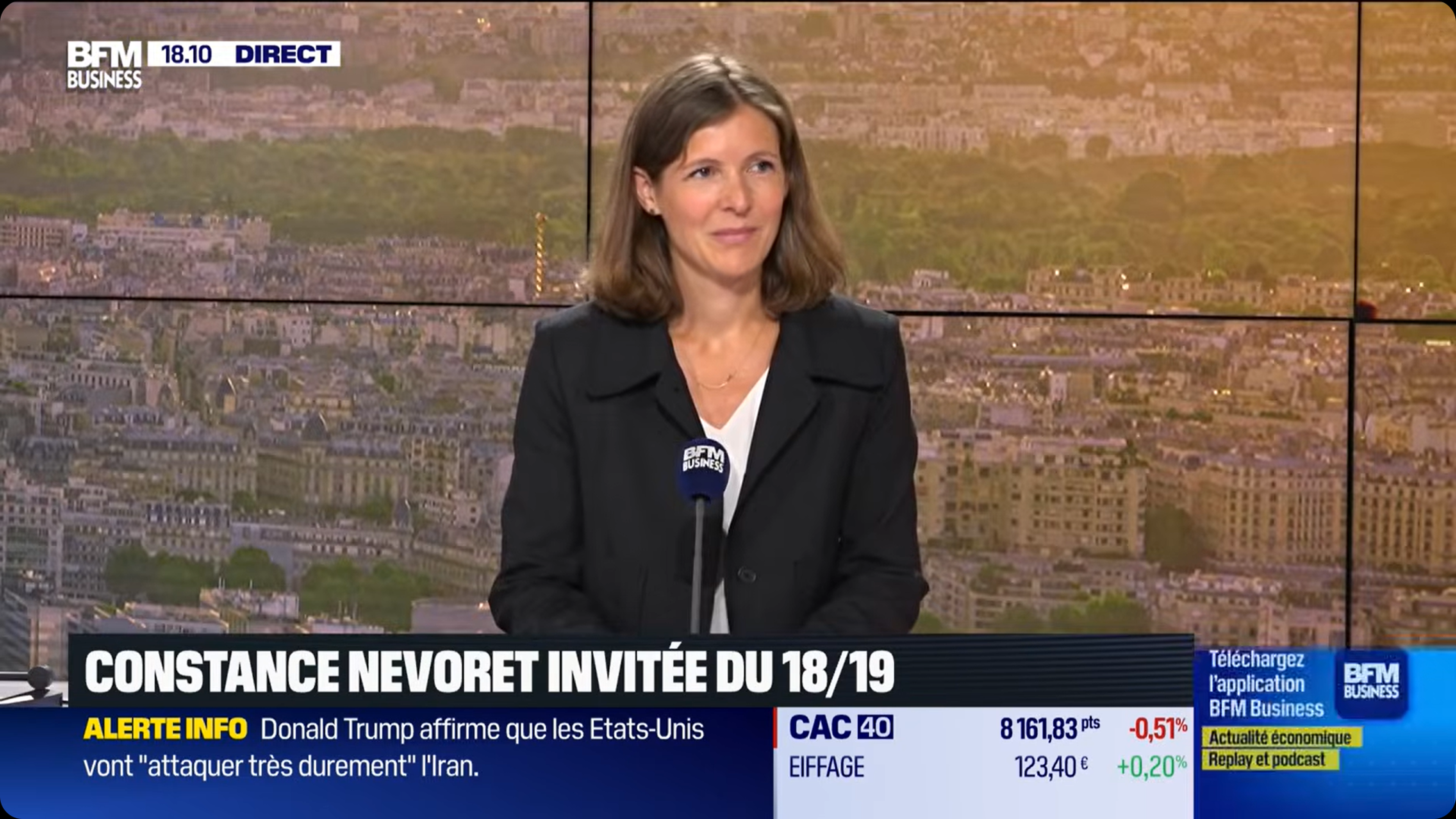 A woman in a black blazer stands at a BFM Business news desk with a cityscape on the screen behind her. News and stock updates display below.