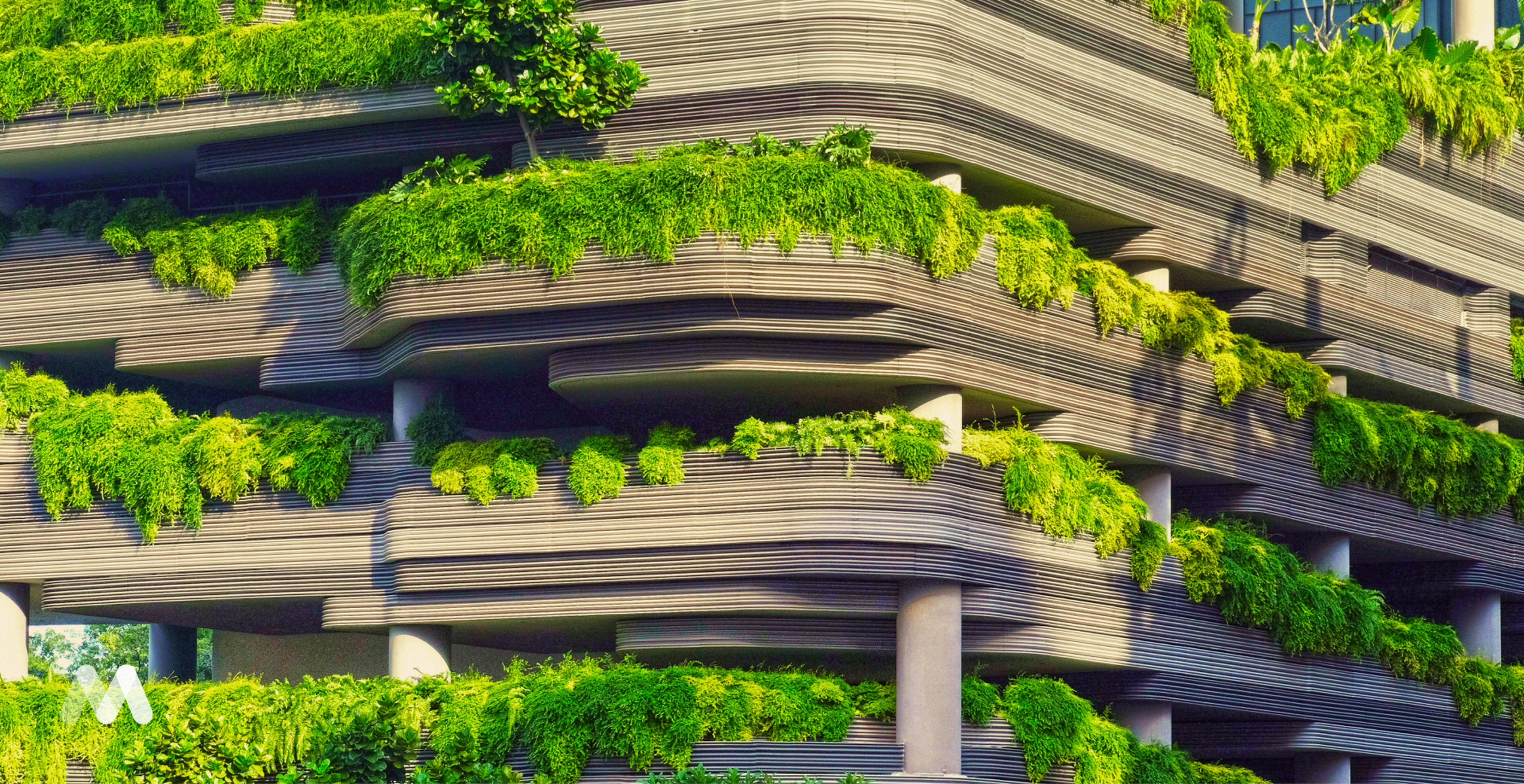Modern building with curved, layered architecture adorned with lush green foliage on each level, blending nature and urban design.
