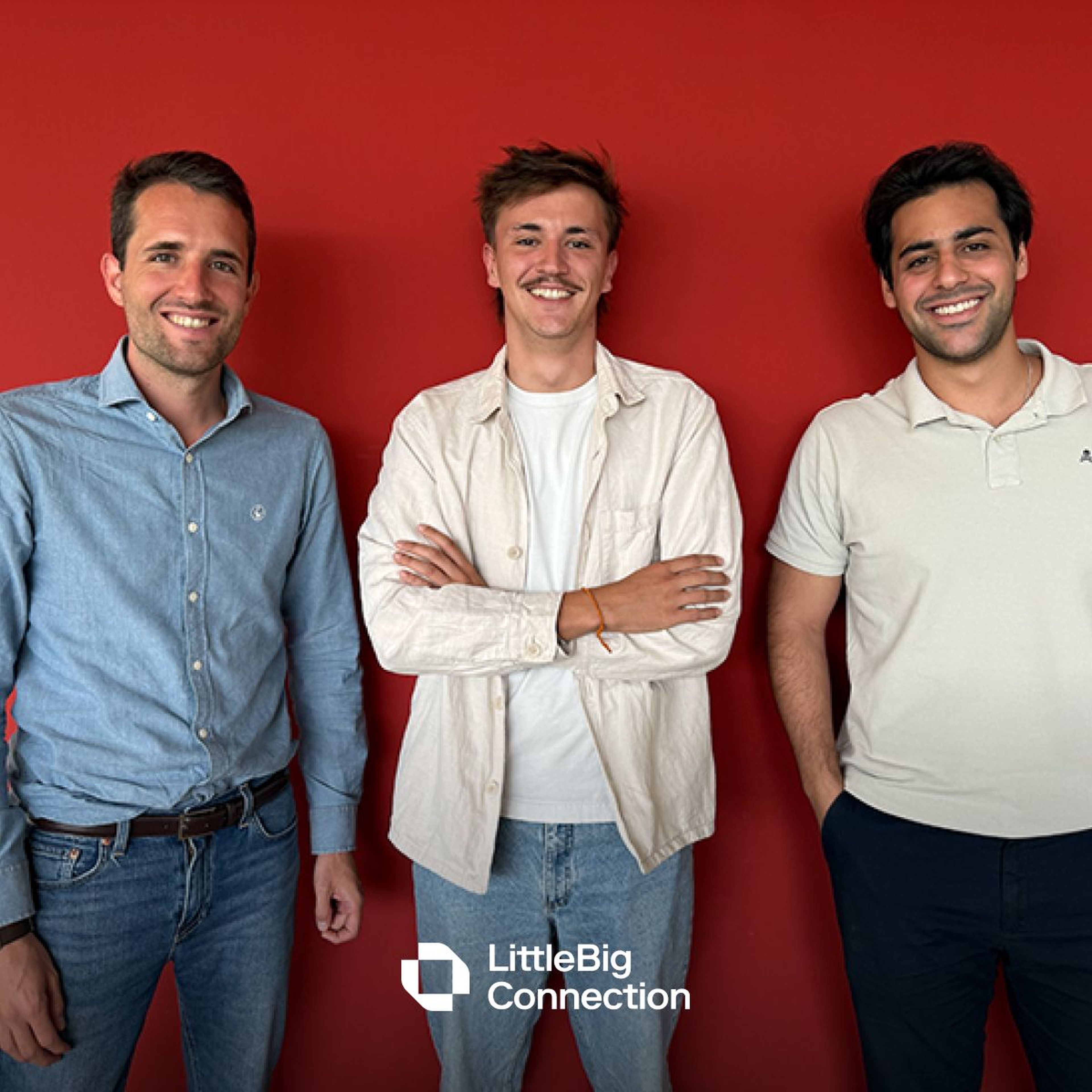 Three smiling men standing against a red wall, wearing casual shirts and jeans, with a logo for LittleBig Connection in the corner.