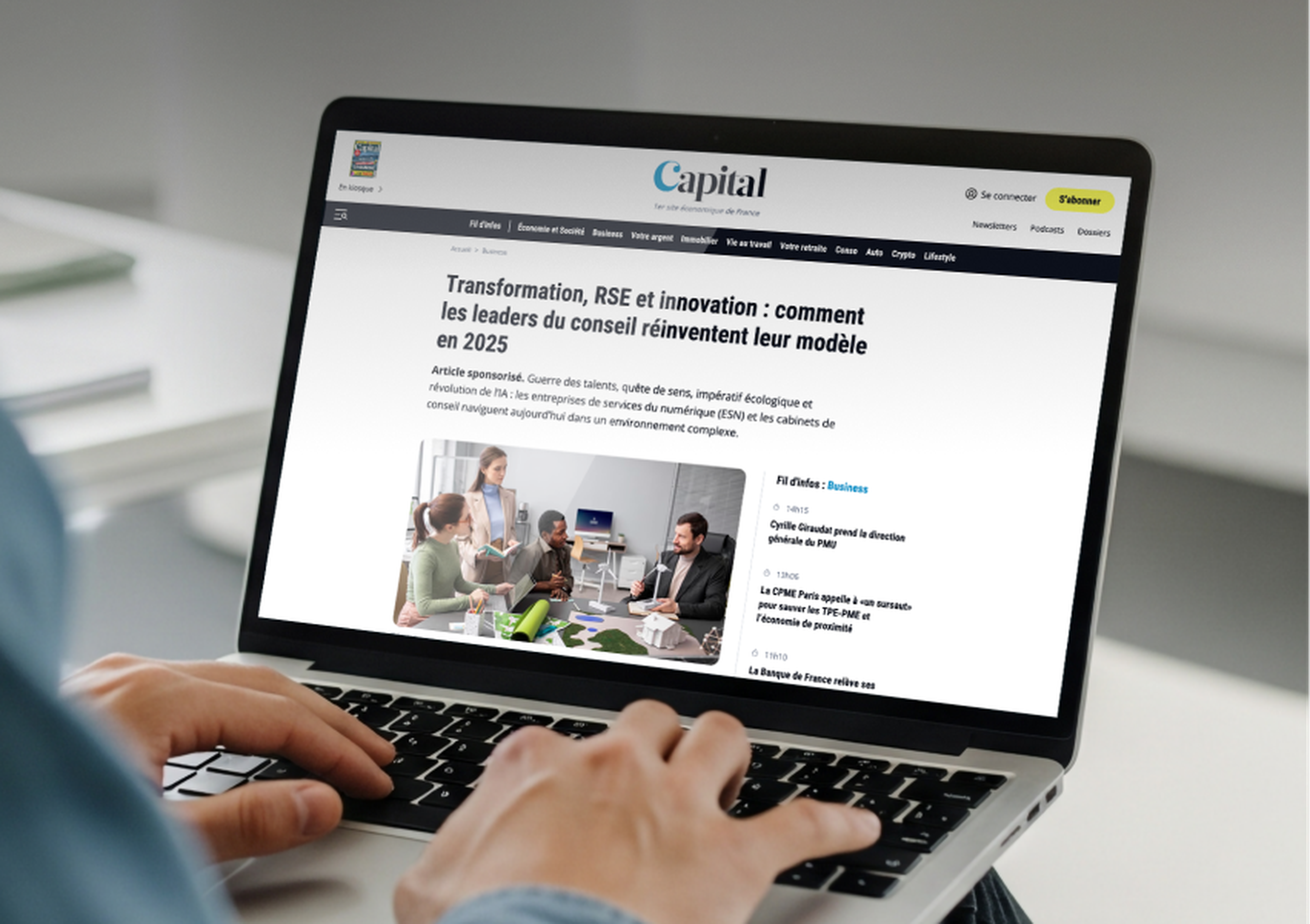 Mains posées sur un ordinateur portable affichant un article du magazine français « Capital » consacré à la transformation, à la RSE et à l'innovation, illustré par une photo d'une réunion d'affaires.