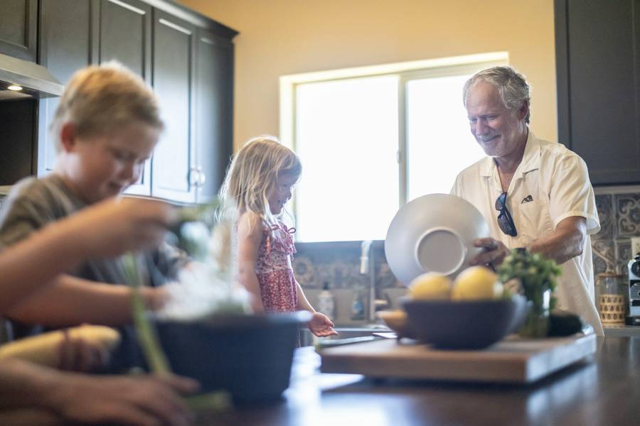 Grandfather cooking together with his grandchildren in a sunny kitchen
