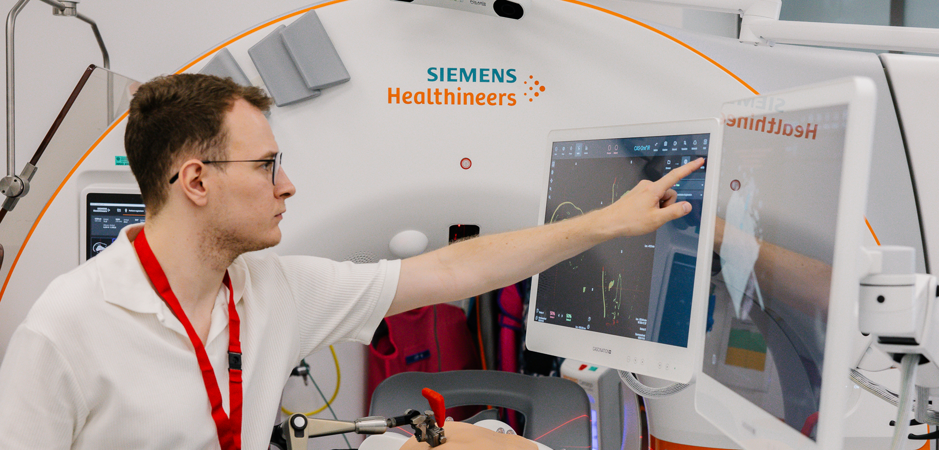 Ein junger Mann berührt den Monitor eines CT-GEräts