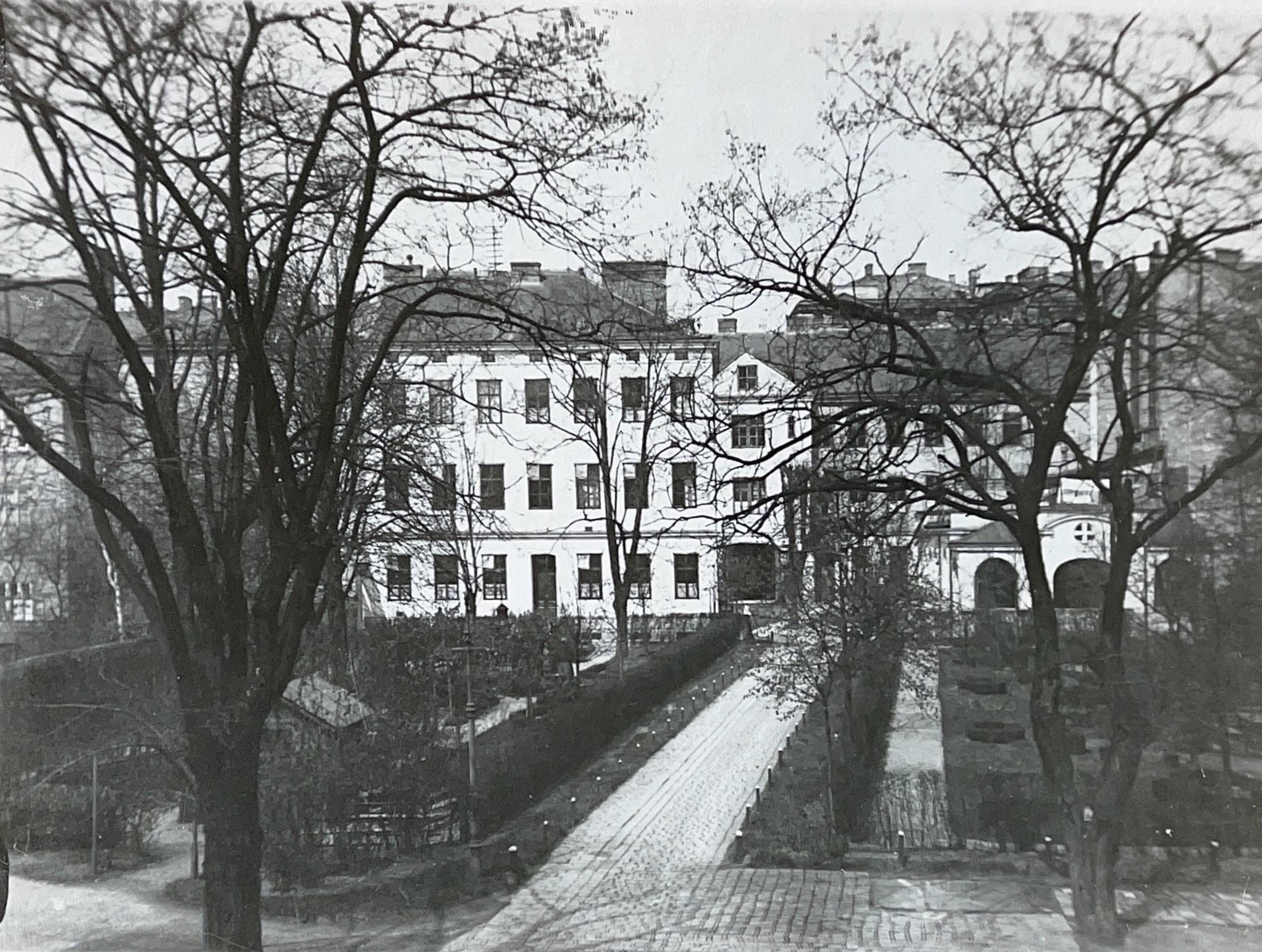 Eine Schwarz-Weiß-Aufnahme aus dem Jahr 1927. Zu sehen ist ein Krankenhaus im damaligen Stil, mit Schwerpunkt auf einen Weg, der zum Eingang führt. Das Gebäude ist gesäumt mit blätterlosen Bäumen.