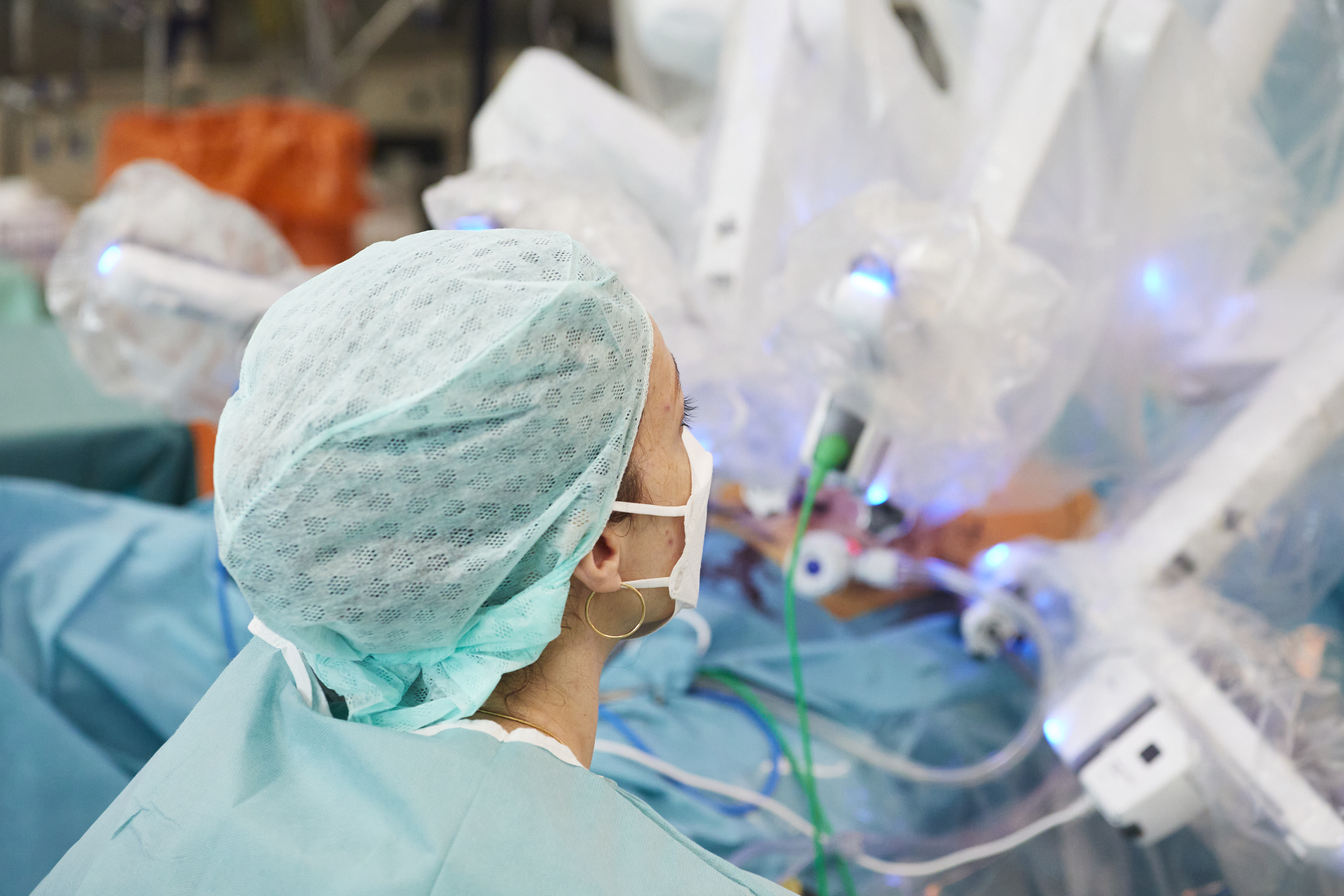 Eine Ärztin in einer Intensivstation steht mit dem Rücken zu uns, unschaft zu sehen ist ein Patient oder eine Patientin, die über Gerätschaften versorgt wird.