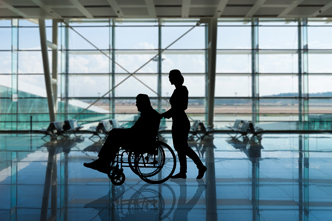 A medical escort assisting someone in a wheelchair