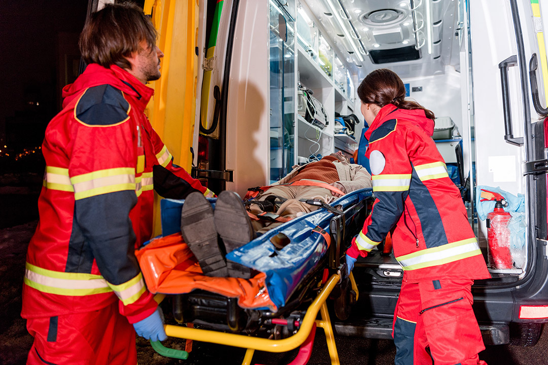 A patient on a stretcher being onboarded on a ground ambulance