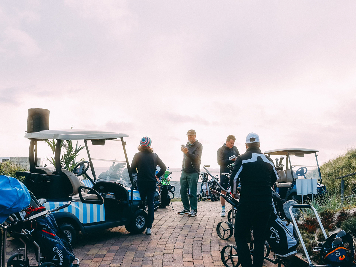 4 Golfspielende mit Golf-Carts und Golf-Ausrüstung.