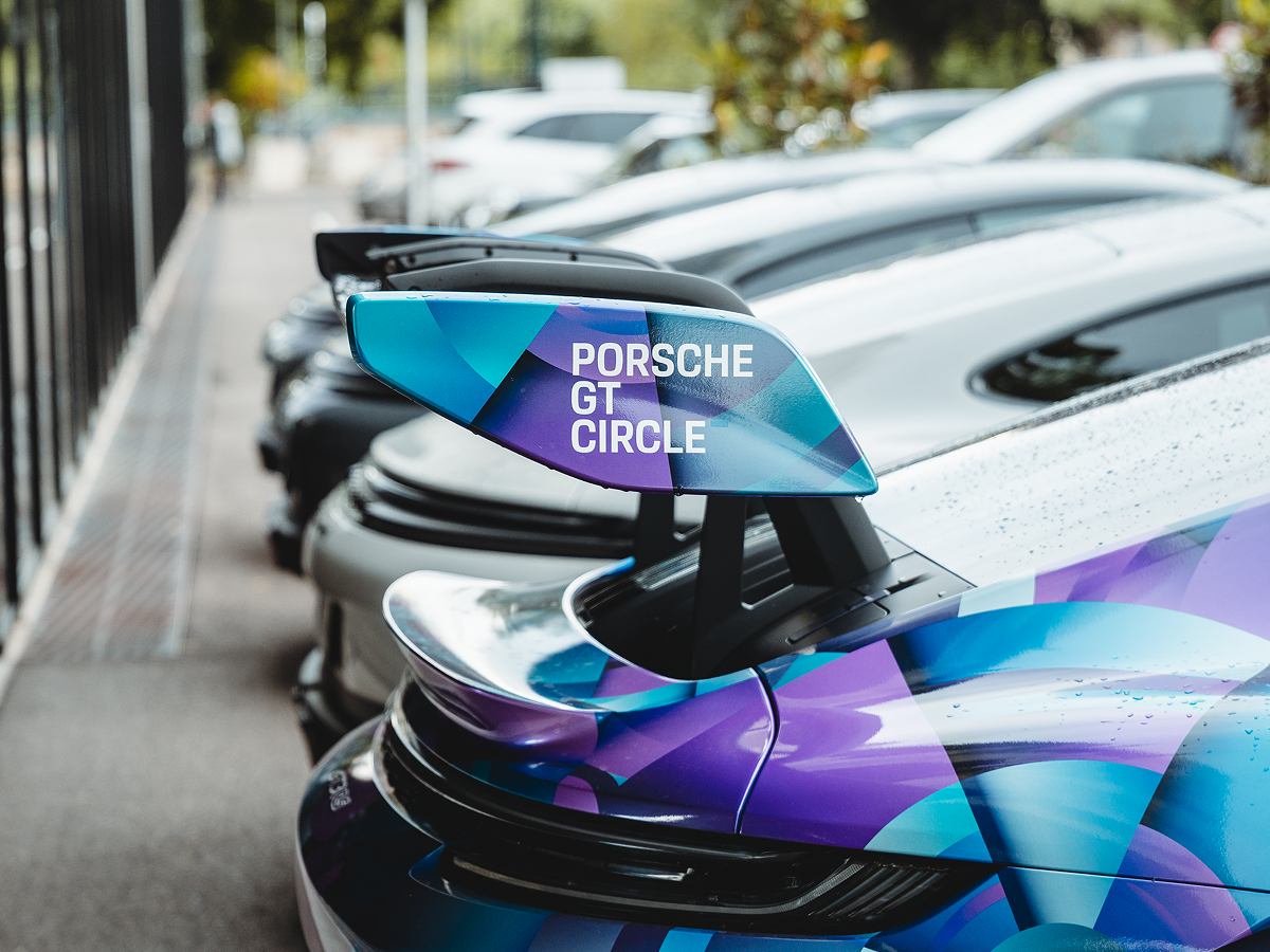 Blick auf die Hecks mehrere Porsche Modelle. Auf dem Sideblade des vordersten Spoilers steht "PORSCHE GT CRICLE".