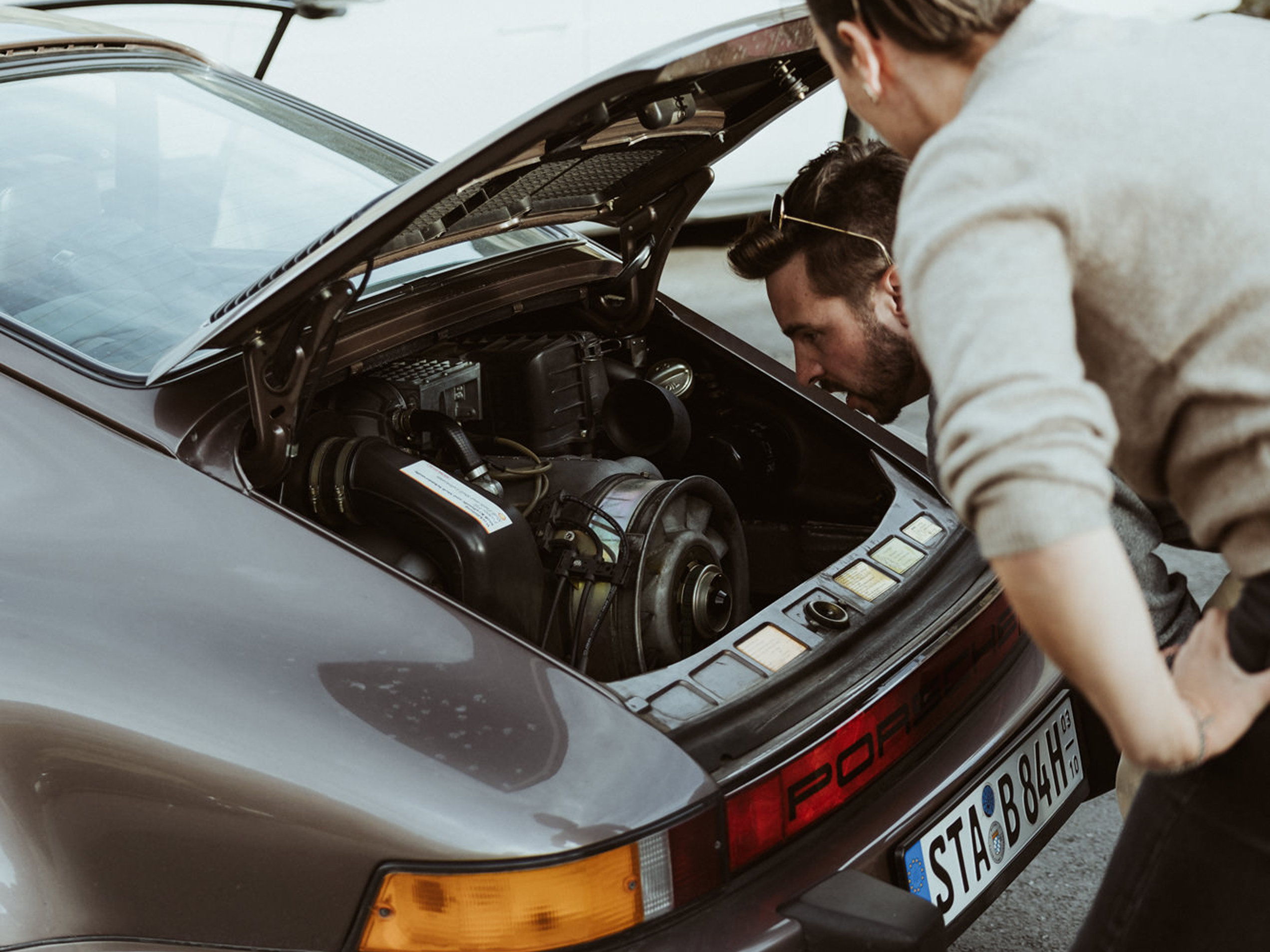 Zwei Männer schauen in den Kofferraum eines Porsche.