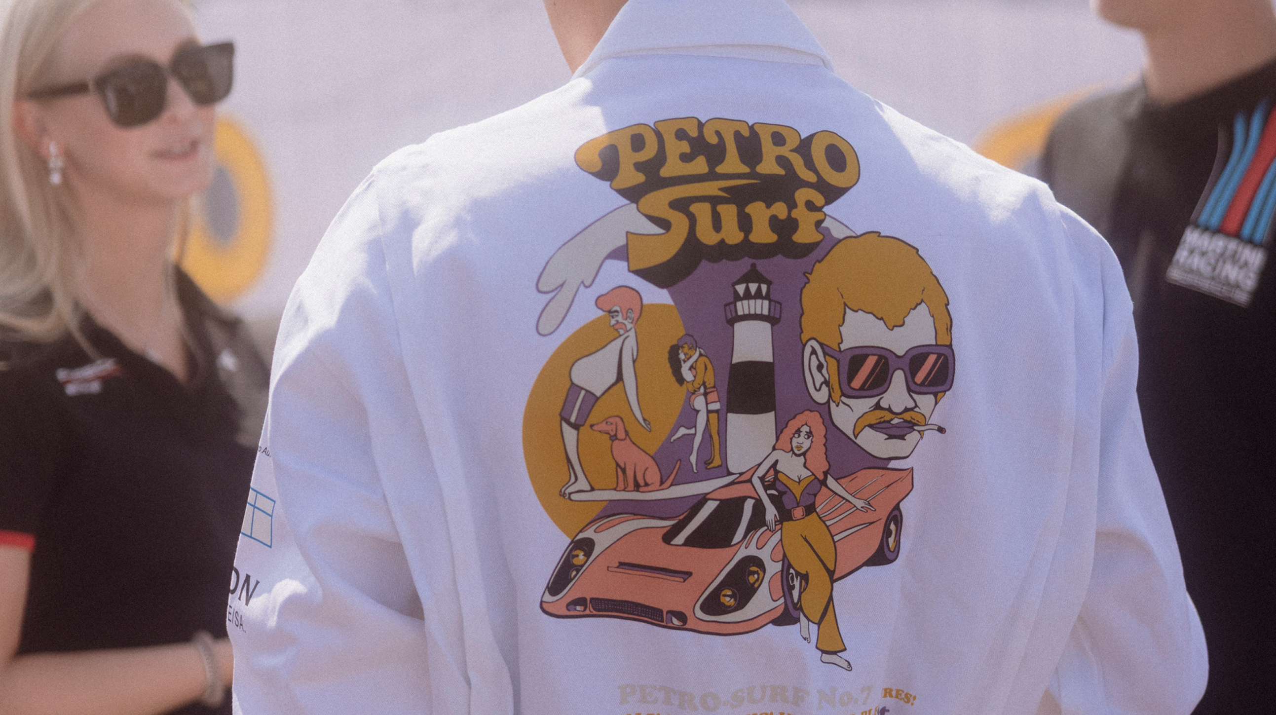 Blick auf den Rücken einer Person, die einen weißen Rennanzug mit Petro Surf Aufdruck trägt.