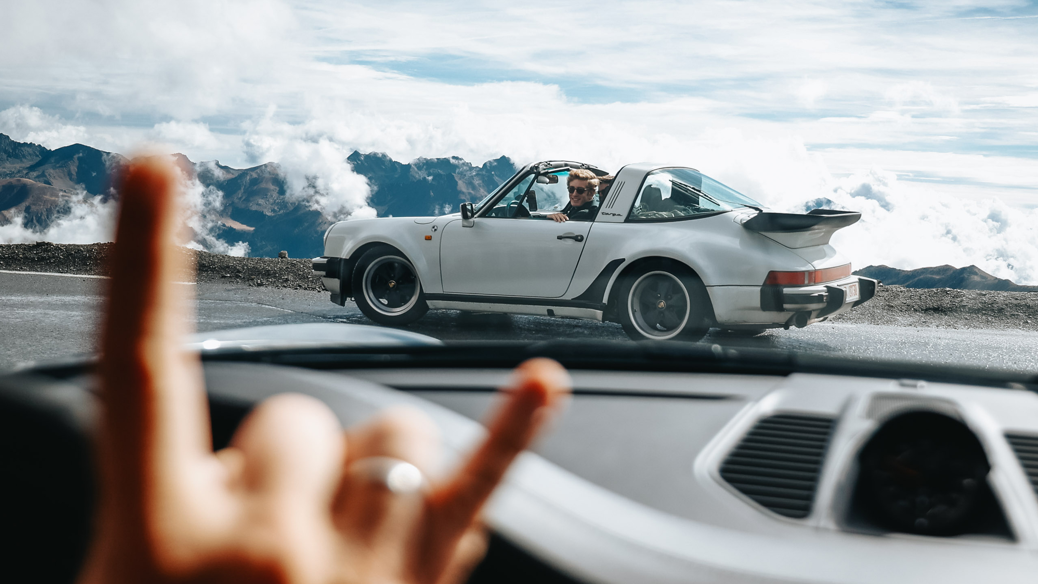 Ein Porsche Oldtimer steht im Profil auf einer Bergstraße.