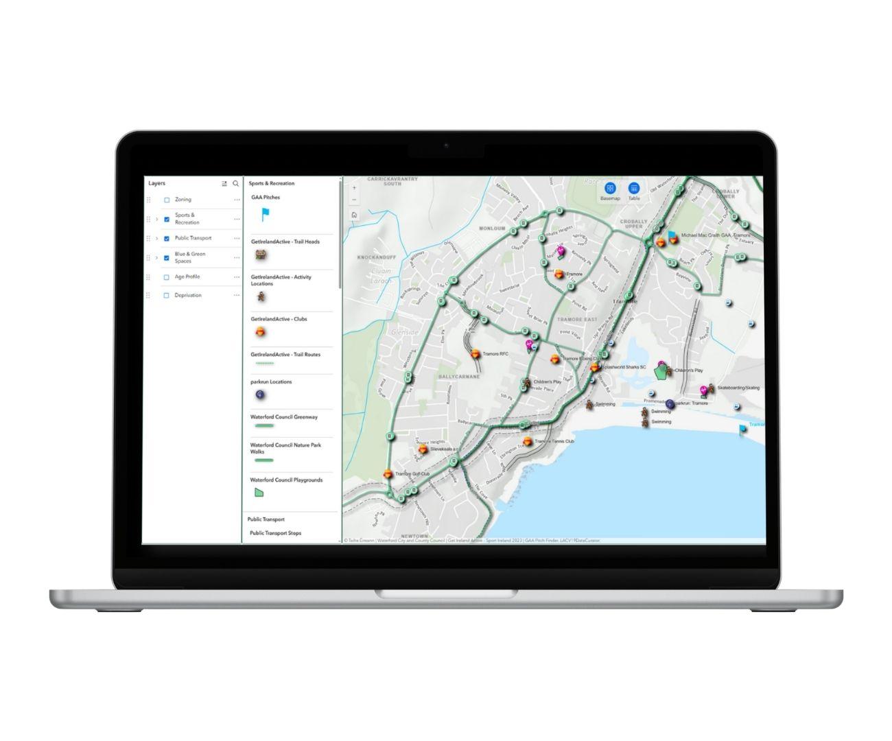 A laptop displaying a detailed city map with locations and routes marked, alongside navigation and layer options on the left sidebar.