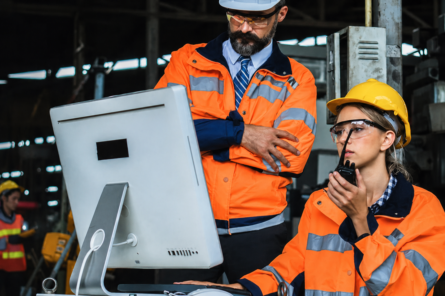 two workers on site in hi vis look at a computer screen