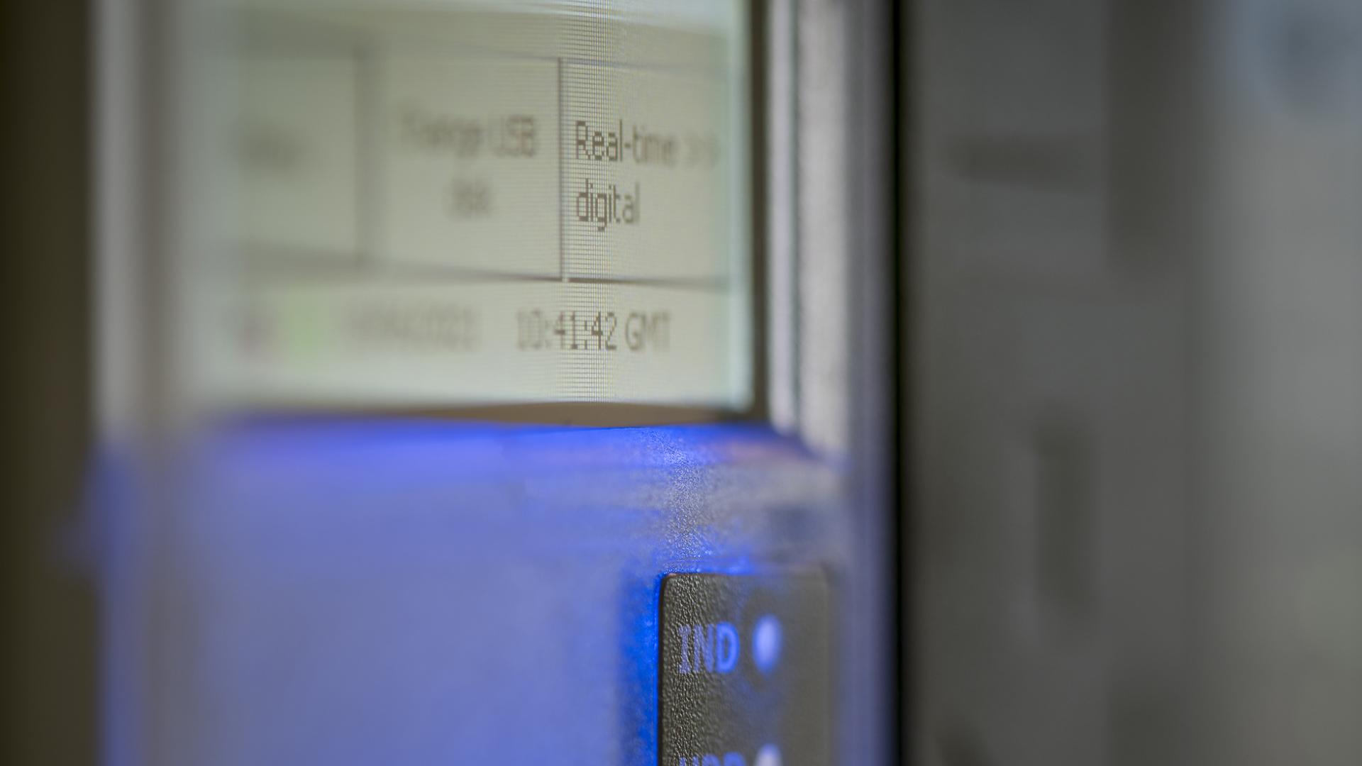 Close-up of a digital display with blurred text and a glowing blue indicator light on a device.