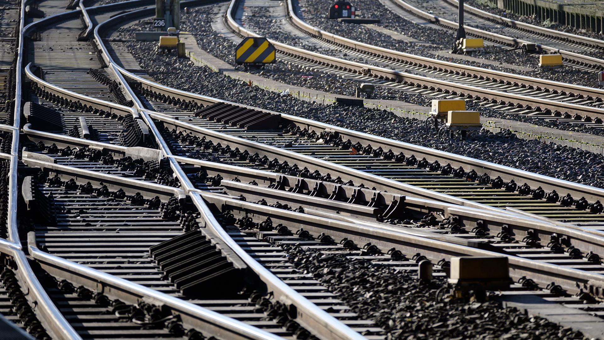 Close-up of multiple railway tracks intersecting and diverging, with sunlight casting shadows on the gravel-covered ground.