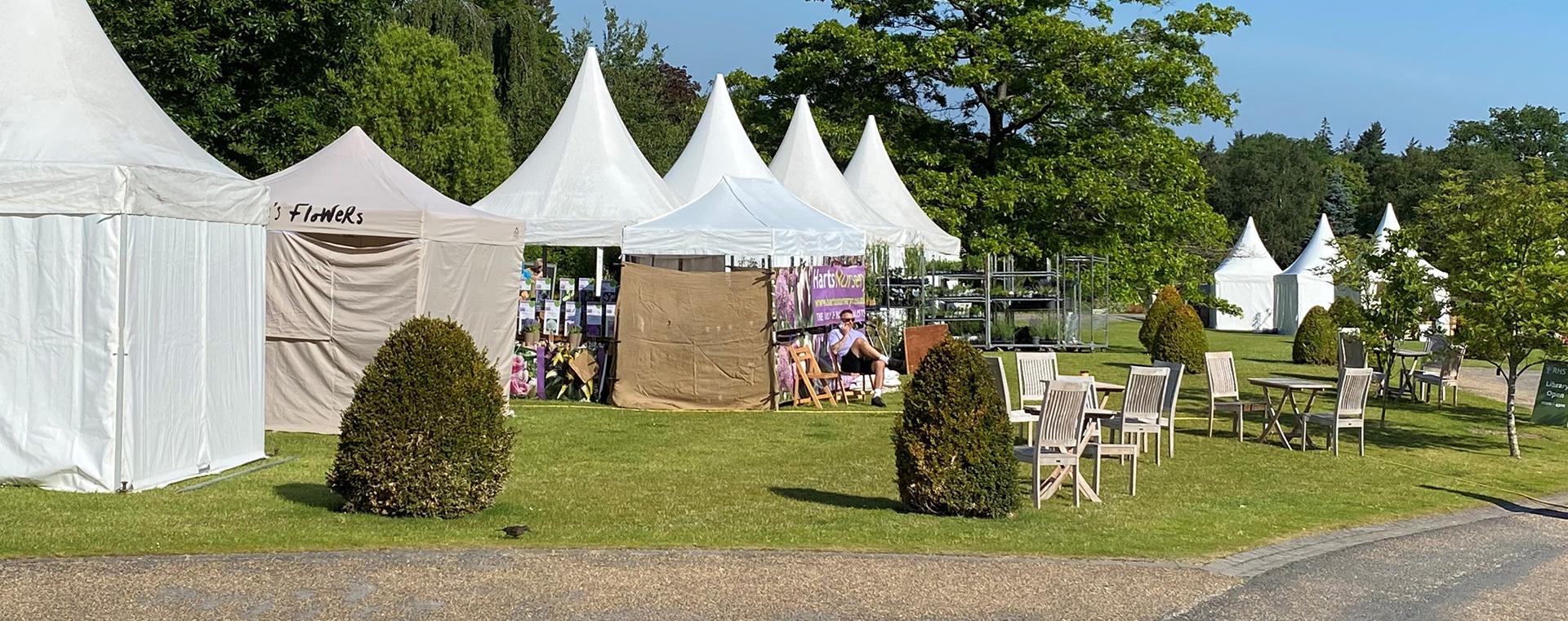 A group of white tents on a grassy area.