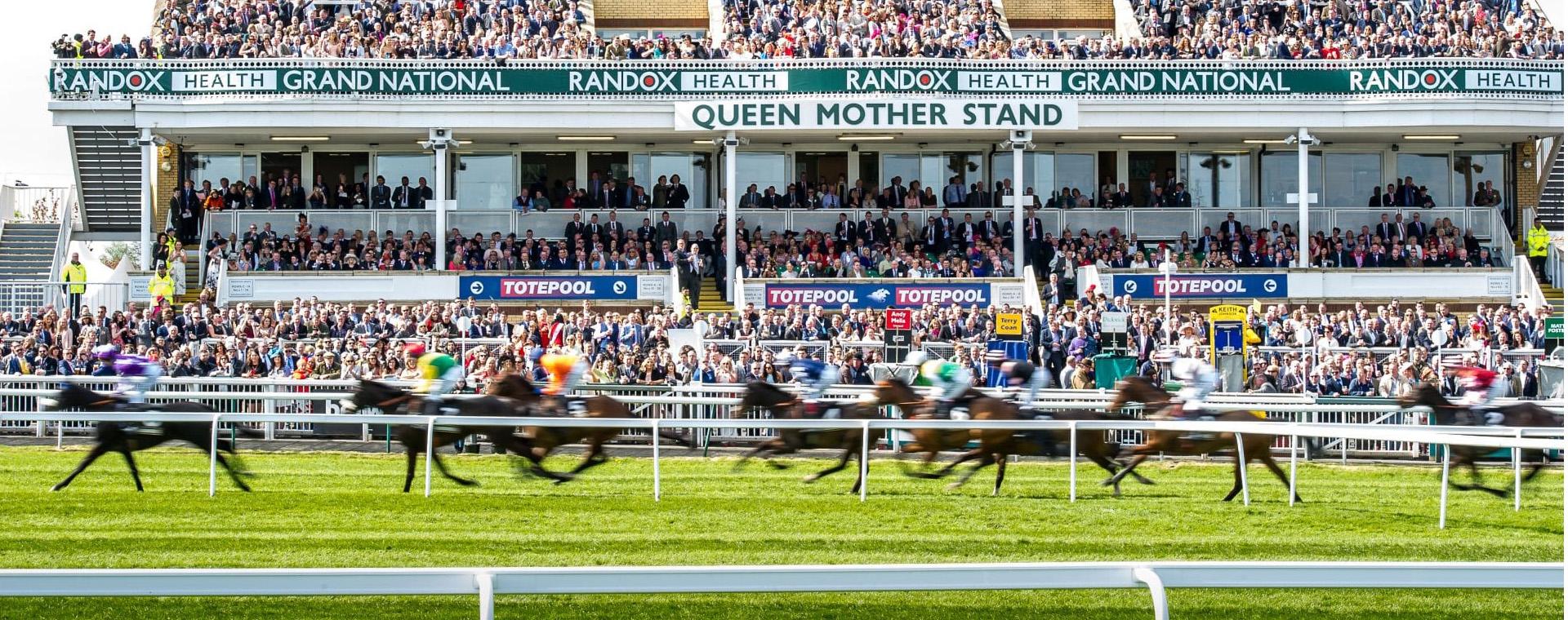 Horses racing past the Queen Mother stand at the Grand National