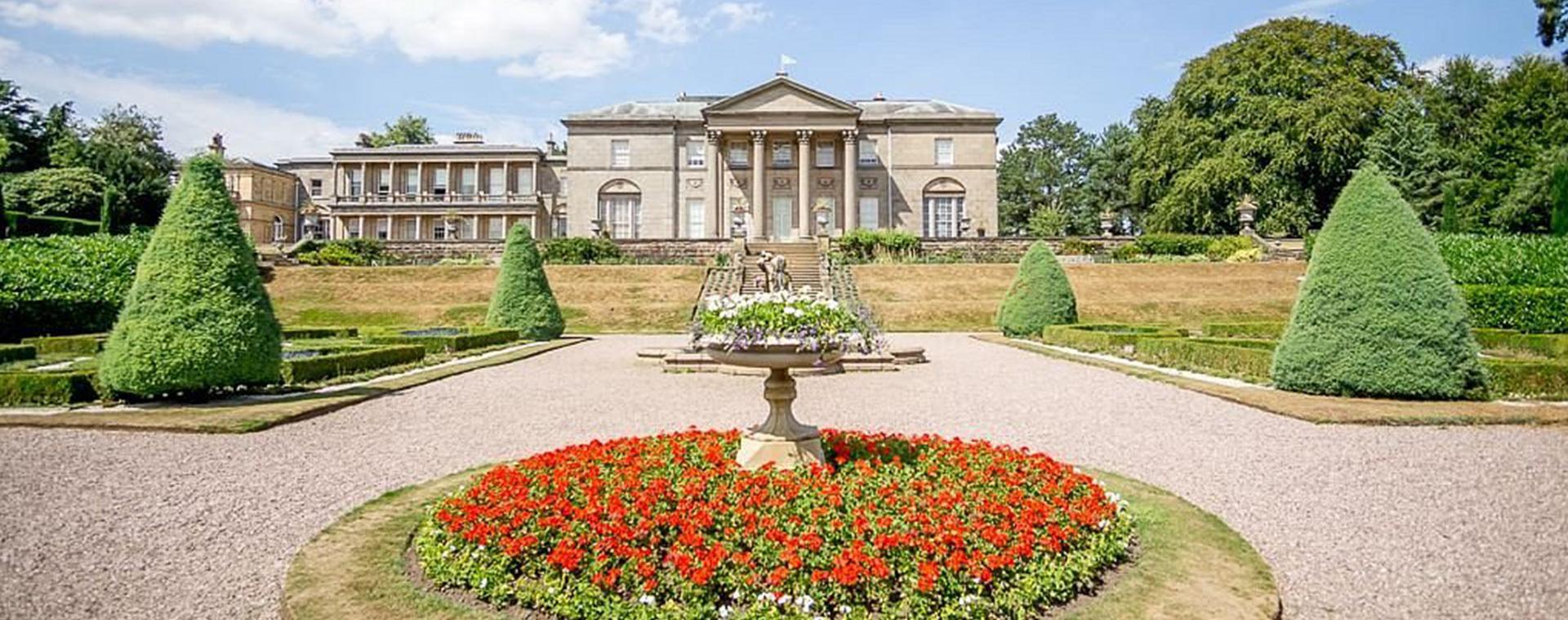 A large mansion with a garden in front of it.