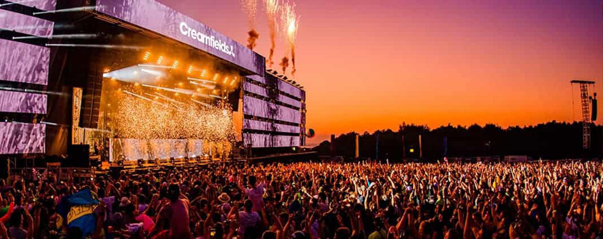 A crowd of people at a concert at dusk.
