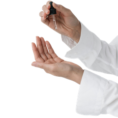 Hands in white sleeves using a dropper to apply liquid onto an open palm, against a plain background.