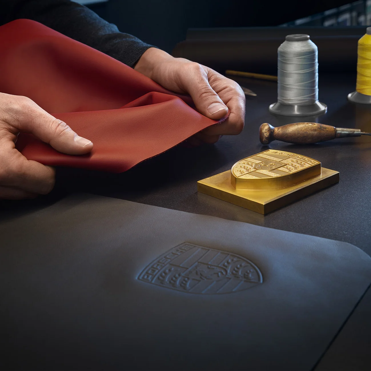 A person is making a printing of the Porsche crest on leather.