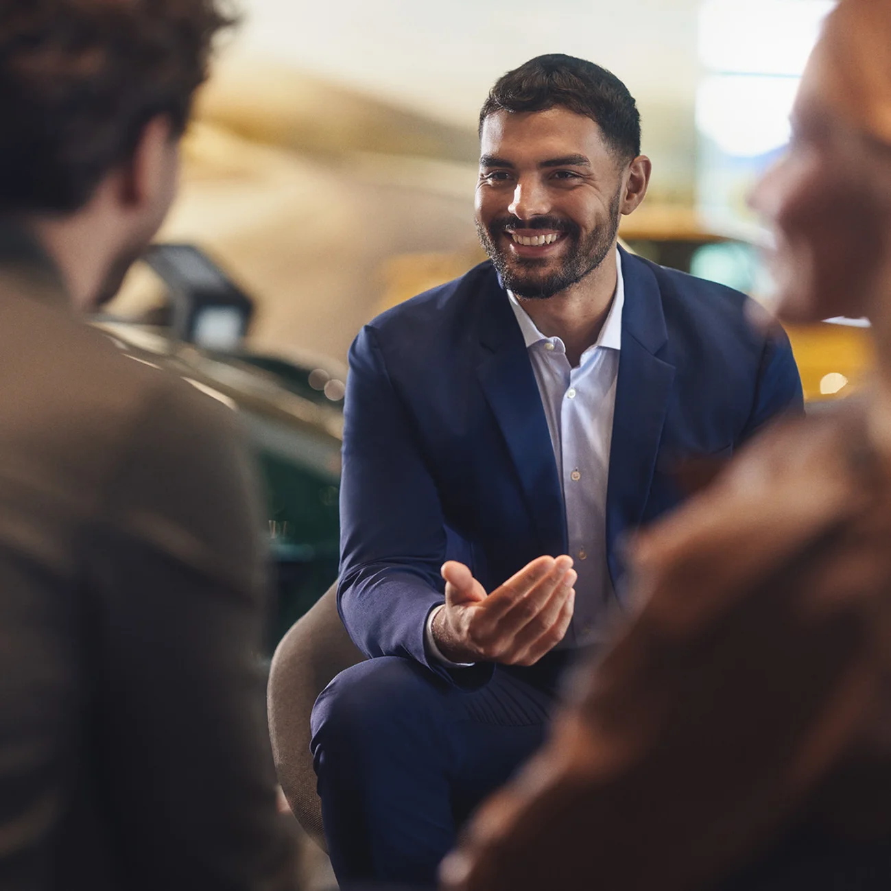 Member of staff talking to two customers in a Porsche Centre.
