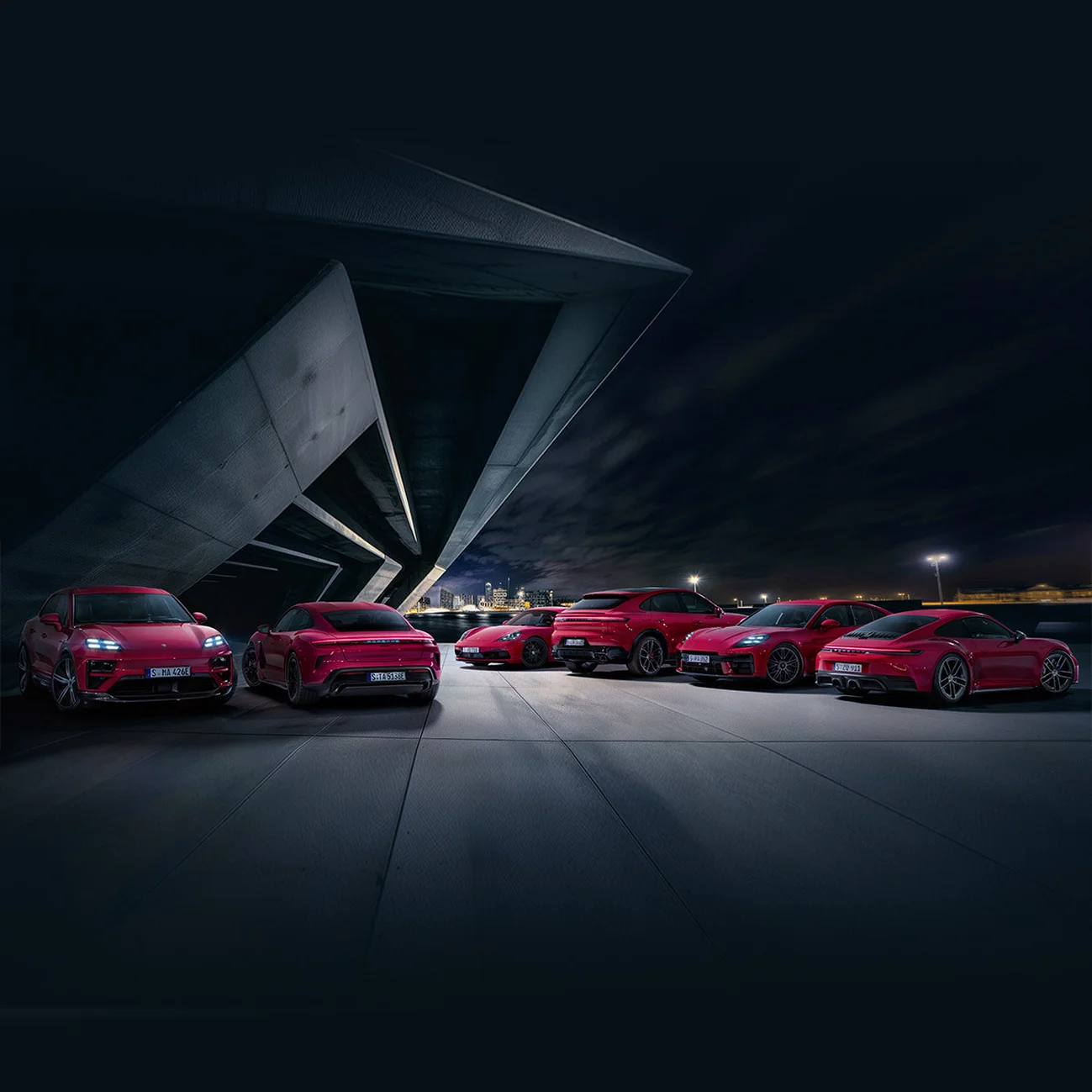 6 red Porsche cars in a parking lot at night