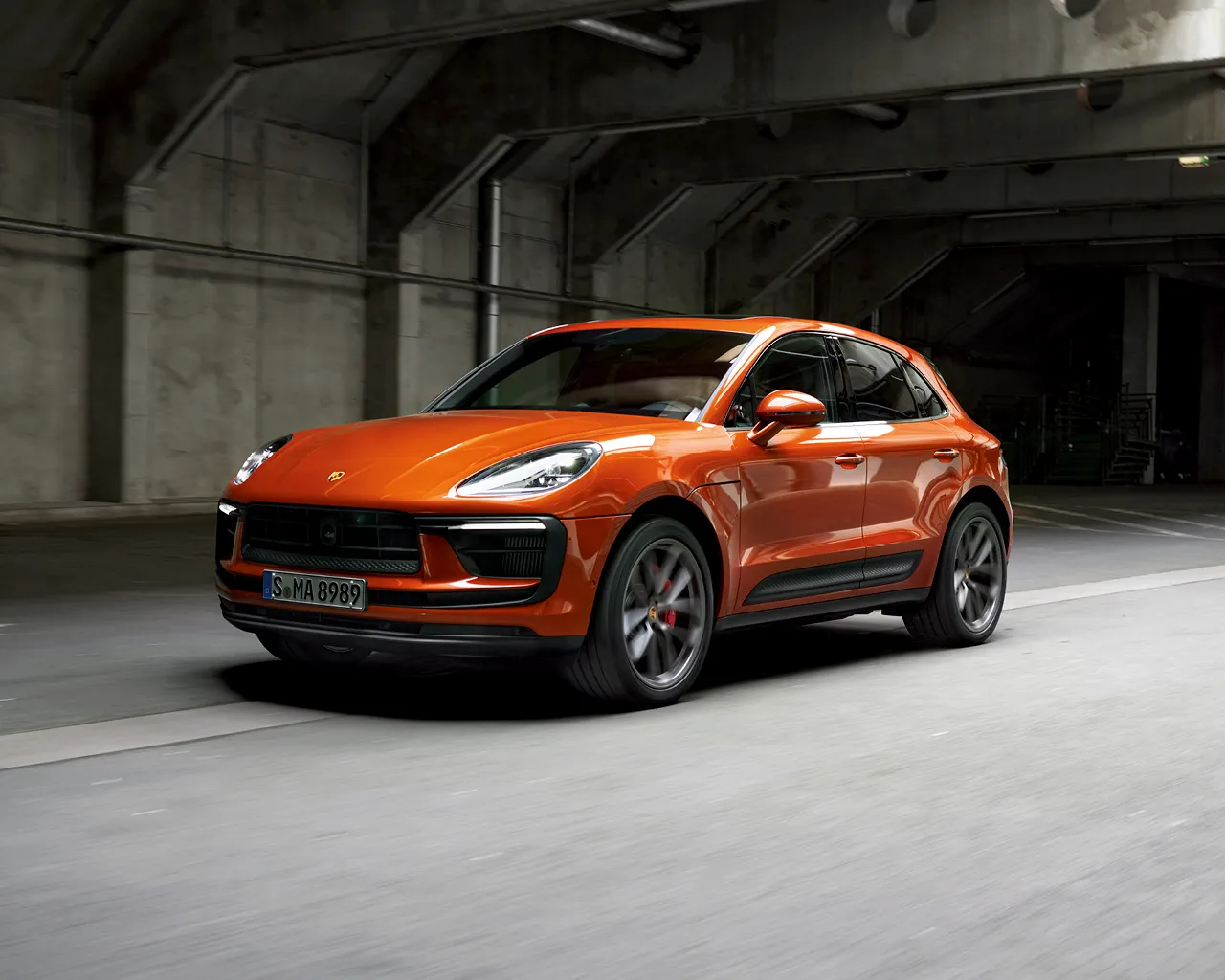 A Porsche Macan driving down a road in an urban scenario.