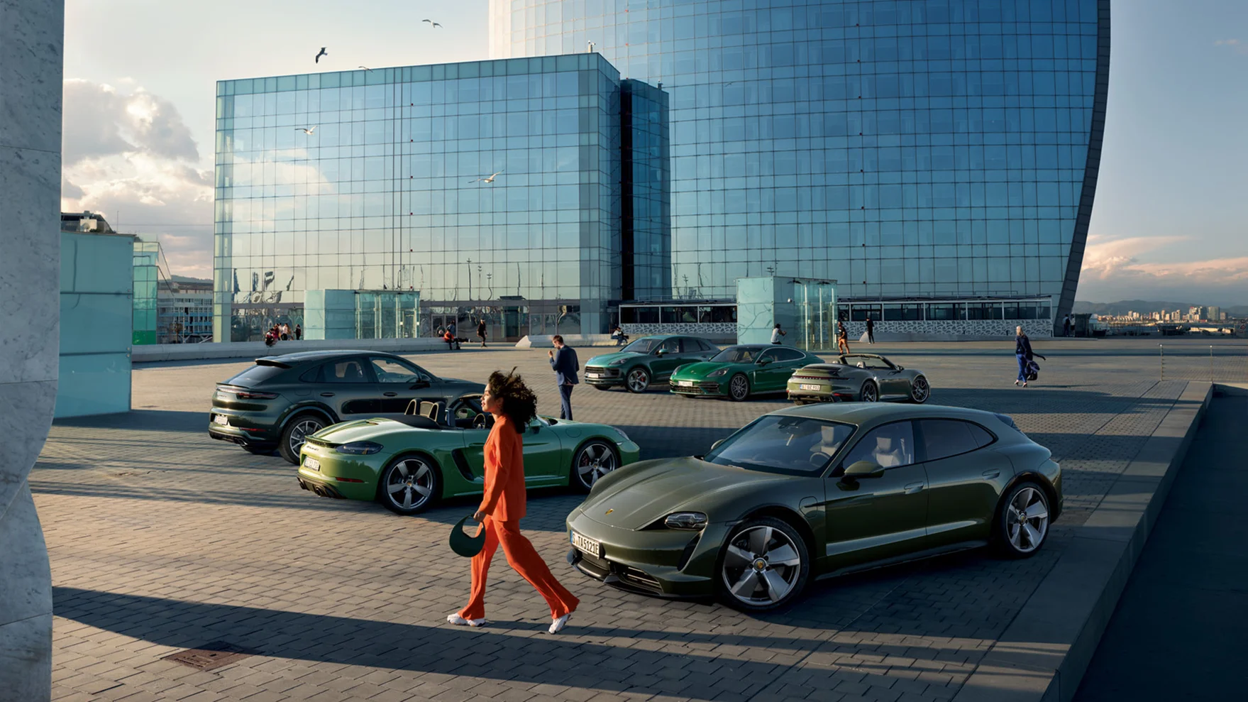 Une femme passe devant plusieurs modèles de Porsche de différentes couleurs.