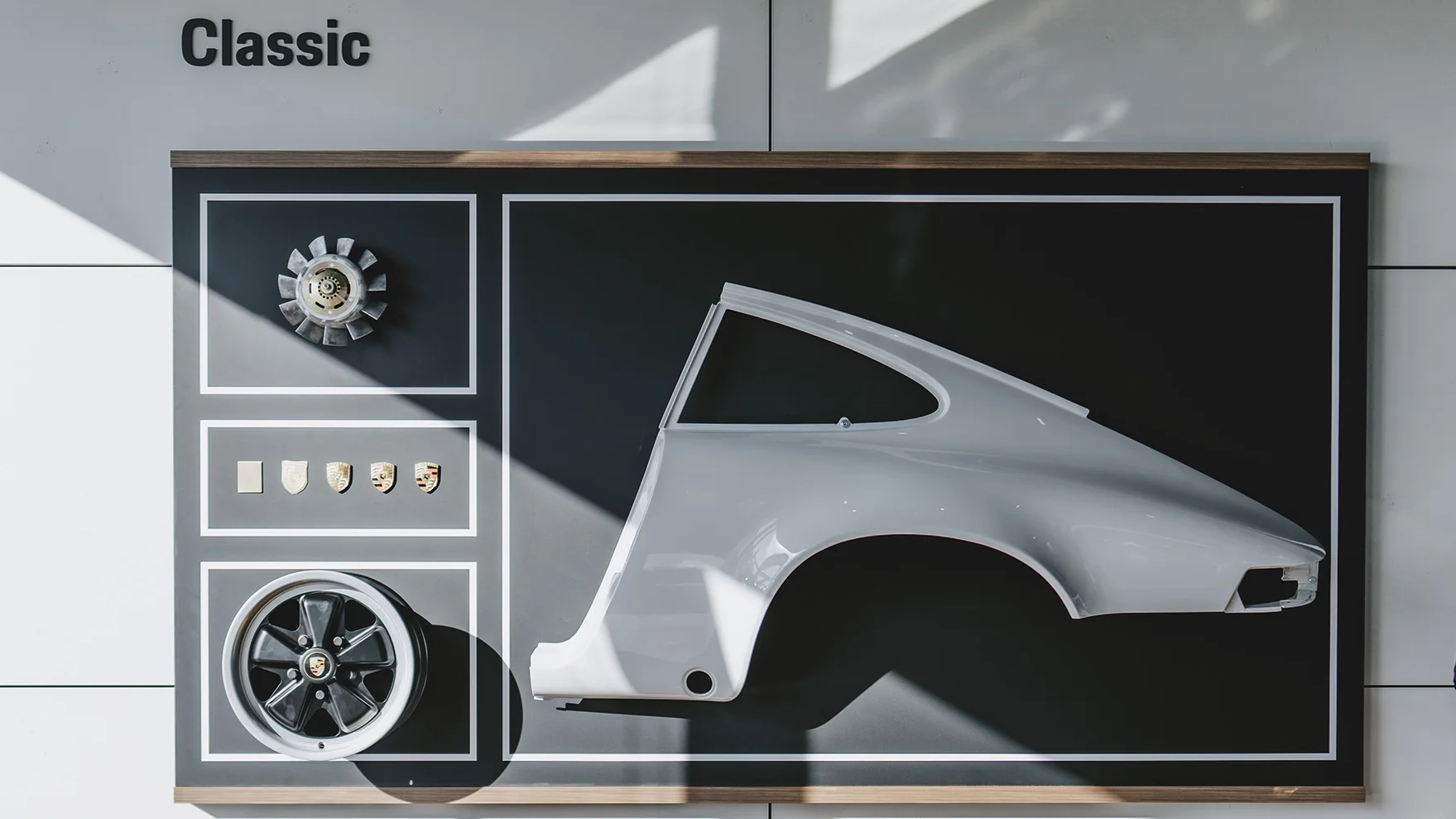 Mur d'exposition avec des pièces Porsche Classic accrochées dans notre showroom Porsche Zenter Roost, en tant que partenaire officiel Porsche Classic.