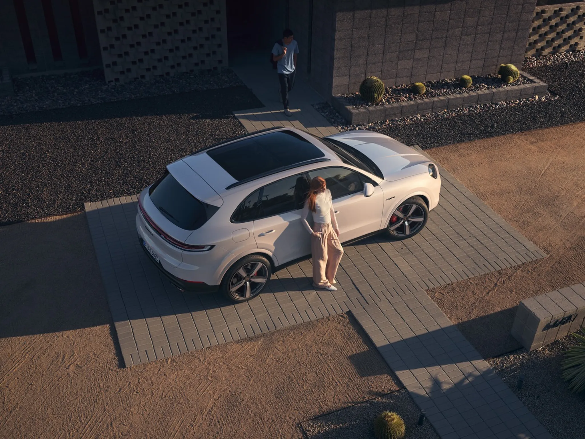Shot from above of a Cayenne S E-Hybrid with a person leaning on the car