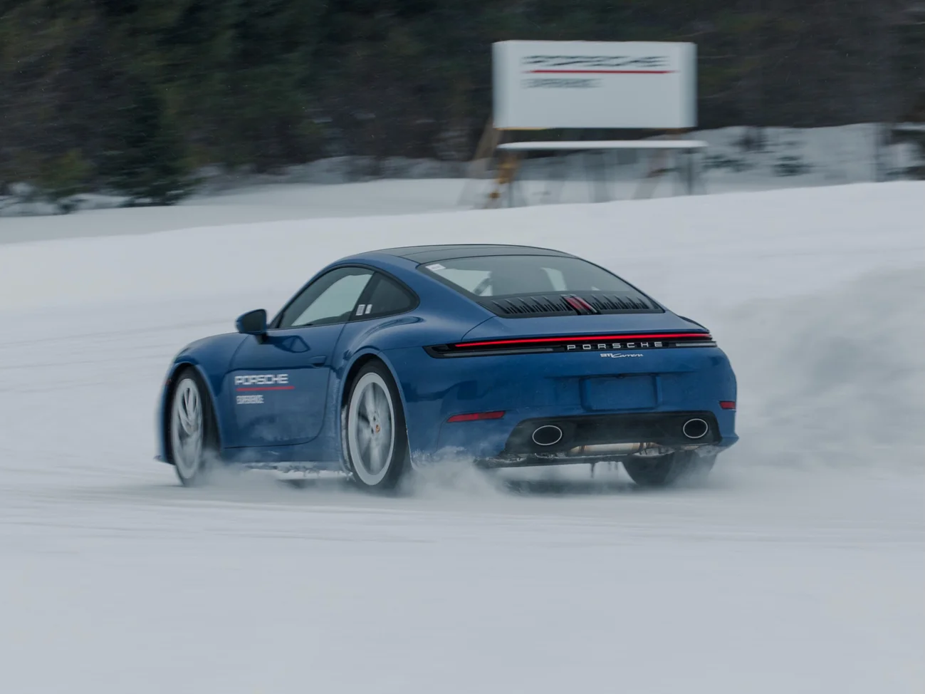 Une Porsche 911 bleue dérapant sur la neige.
