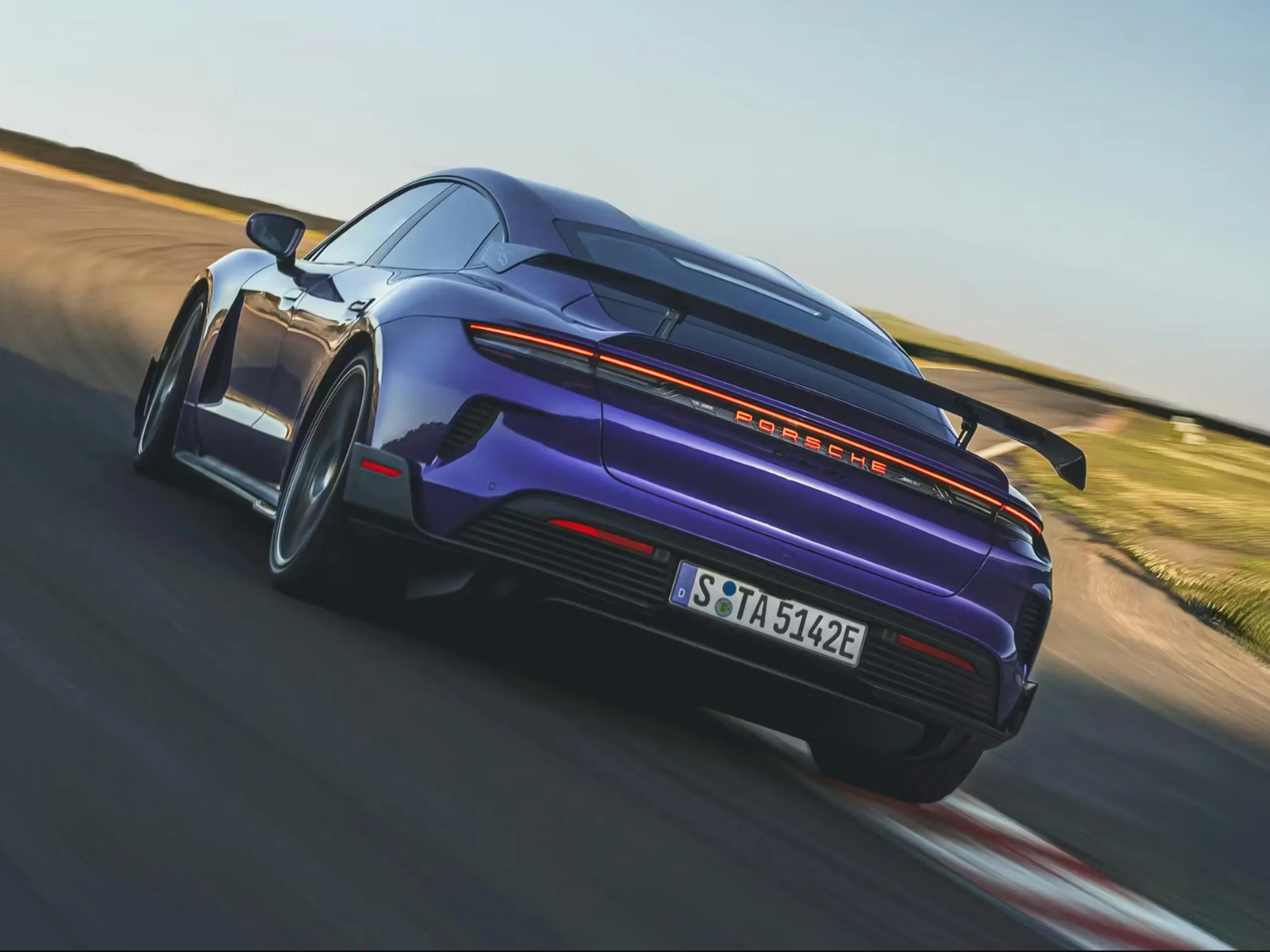 A purple Porsche driving on a circuit.