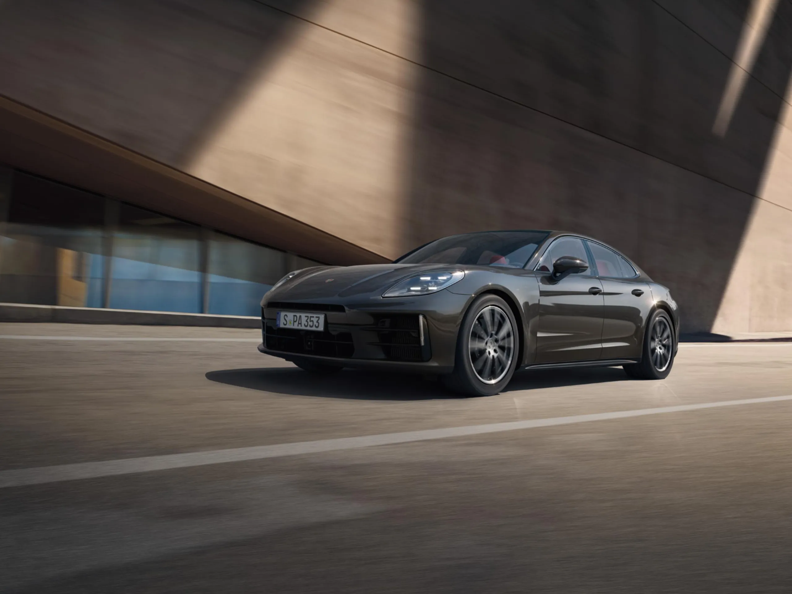 Front shot of the new Panamera 4  in grey driving on the road next to modern buildings.