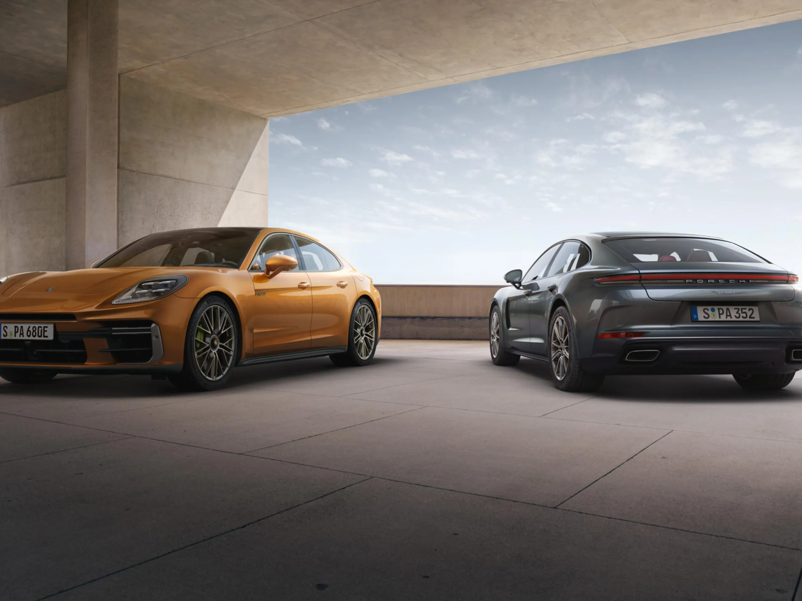 An orange and grey Porsche Panamera parked in a modern parking structure.